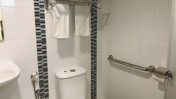 A bathroom with a toilet, a sink, a shower with a grab bar, and a towel rack.