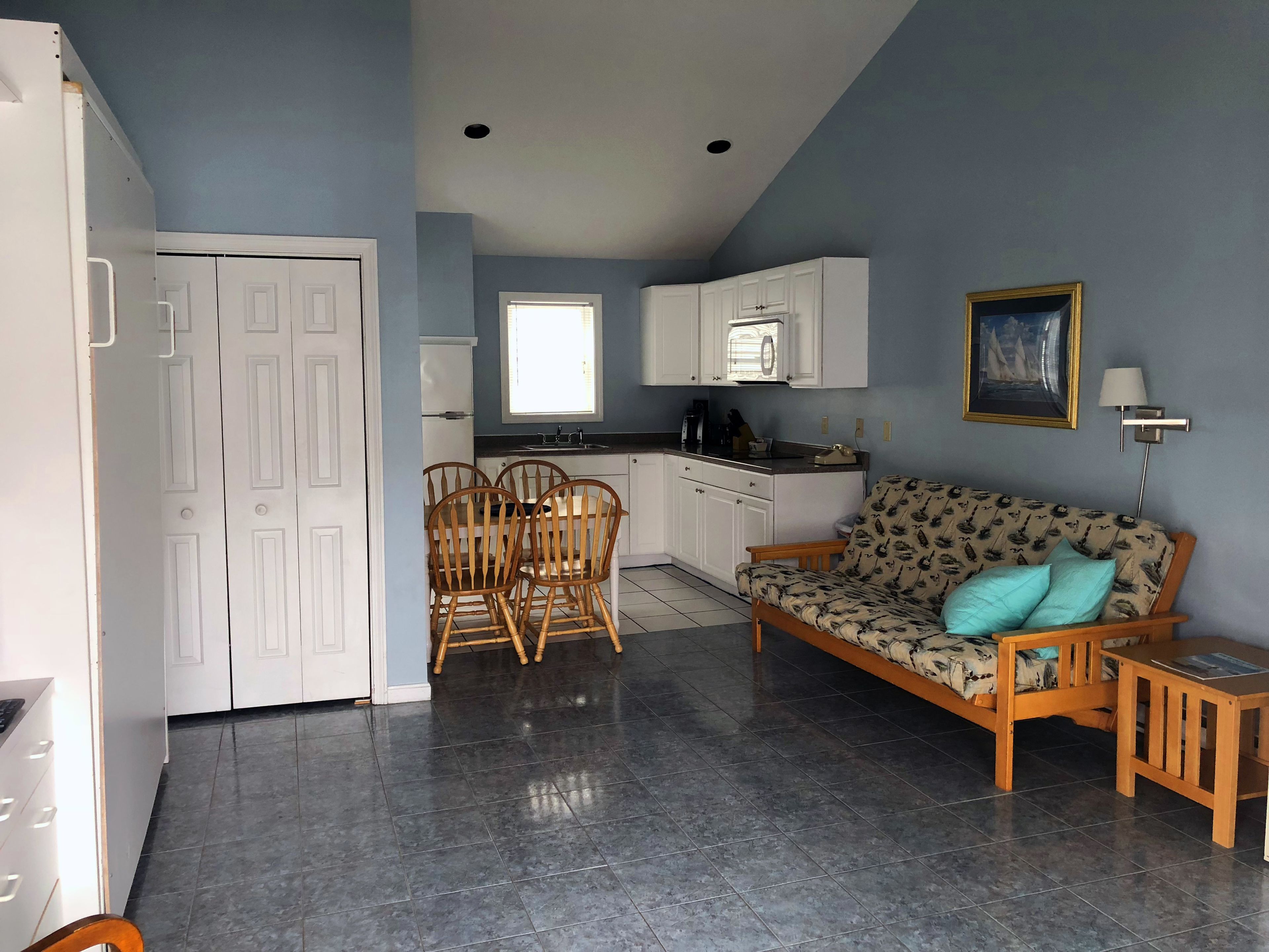 Un espacio habitable compacto con kitchenette, comedor y sofá de tapicería estampada.