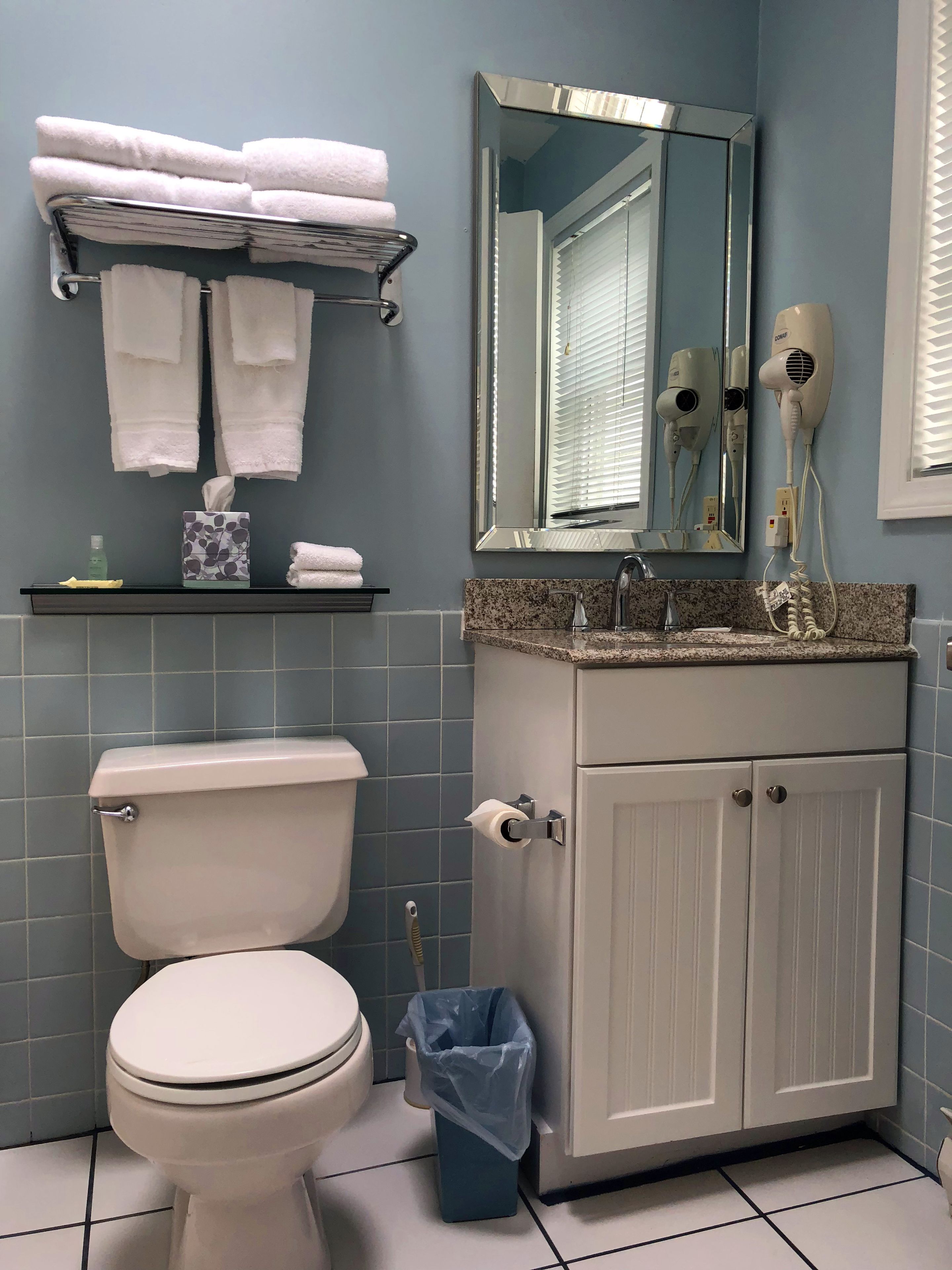 Ett badrum med en toalett, ett handfat med spegel och en handdukshängare med handdukar.