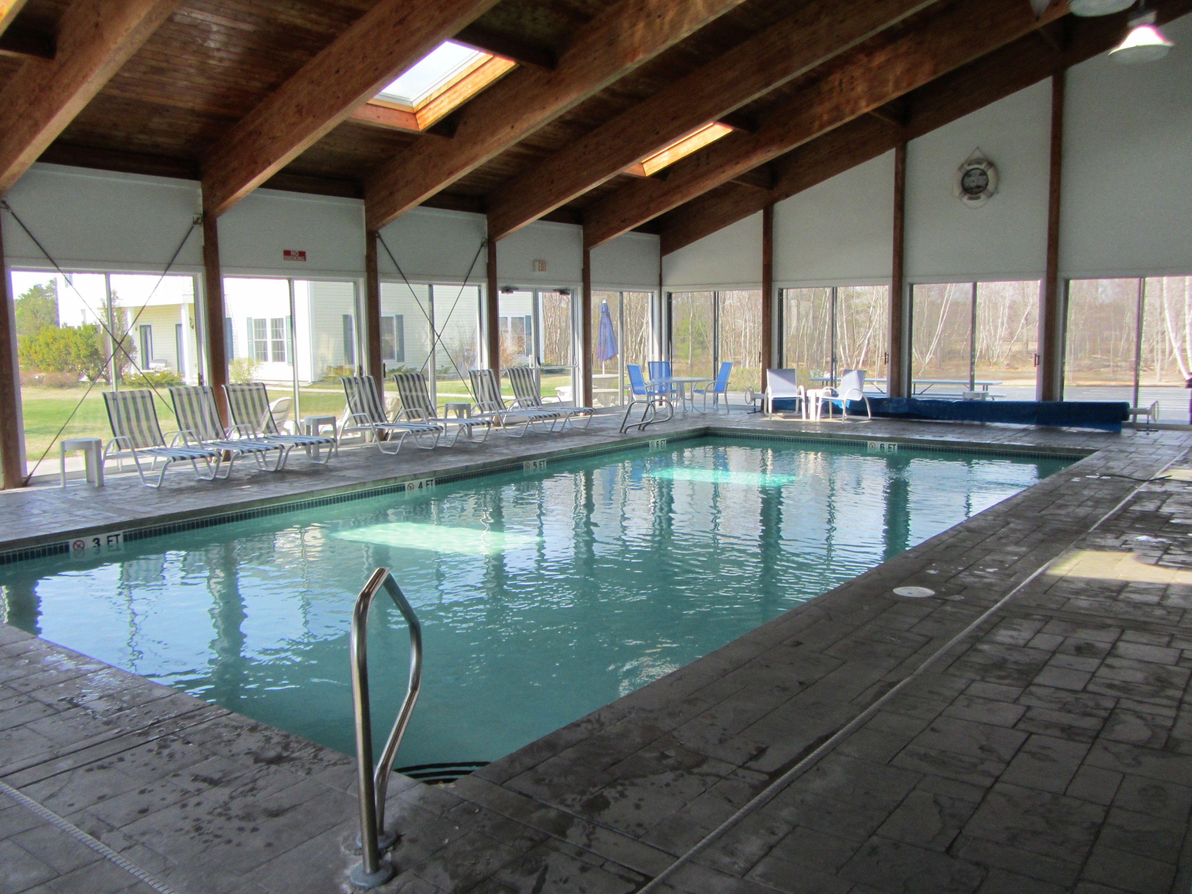 Una piscina interna con acqua cristallina, circondata da lettini prendisole e una struttura coperta.