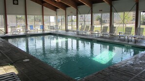 Una piscina interior con agua cristalina, rodeada de sillas de descanso y una cubierta.
