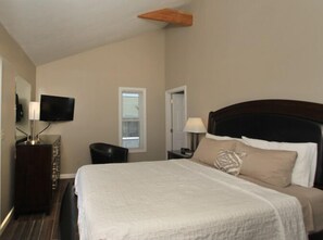 A hotel room with a bed, a TV, a dresser, and a window.