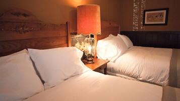 A hotel room with two beds, a wooden headboard, a bedside lamp, and a framed picture on the wall.