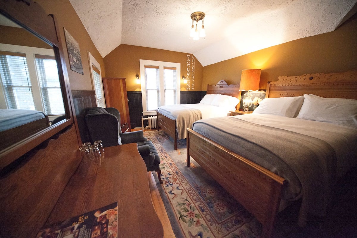 A hotel room with a wooden bed, a desk, a chair, and a window.