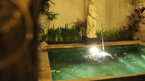 A serene indoor garden with a statue, a fountain, and lush greenery. - Kubu Soca Villa (Ubud)