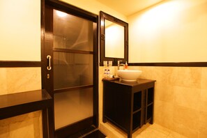 Un baño con tocador de madera oscura, un lavabo blanco y un espejo encima.