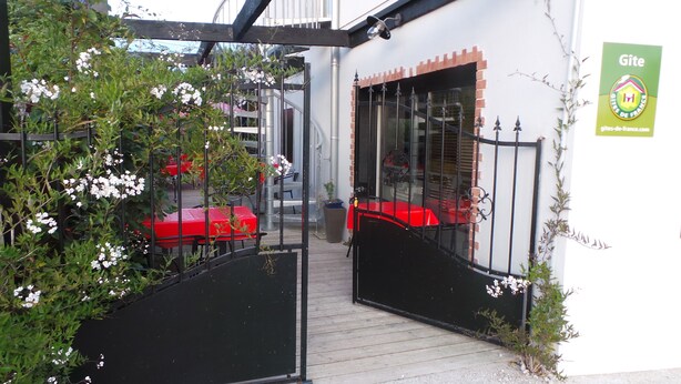 Una entrada cerrada a un edificio con una mesa y sillas rojas afuera.