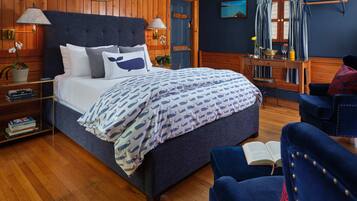 A neatly arranged bedroom with a bed, bedside tables, a reading chair, and a desk.