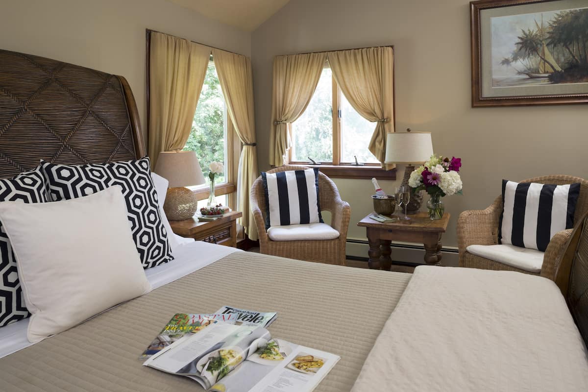 A hotel room with a large bed, two armchairs, a small table with a lamp, and a painting on the wall.