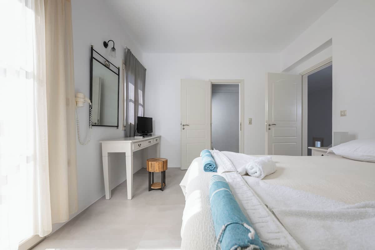 Een hotelkamer met een bed, een bureau, een spiegel en een deur.