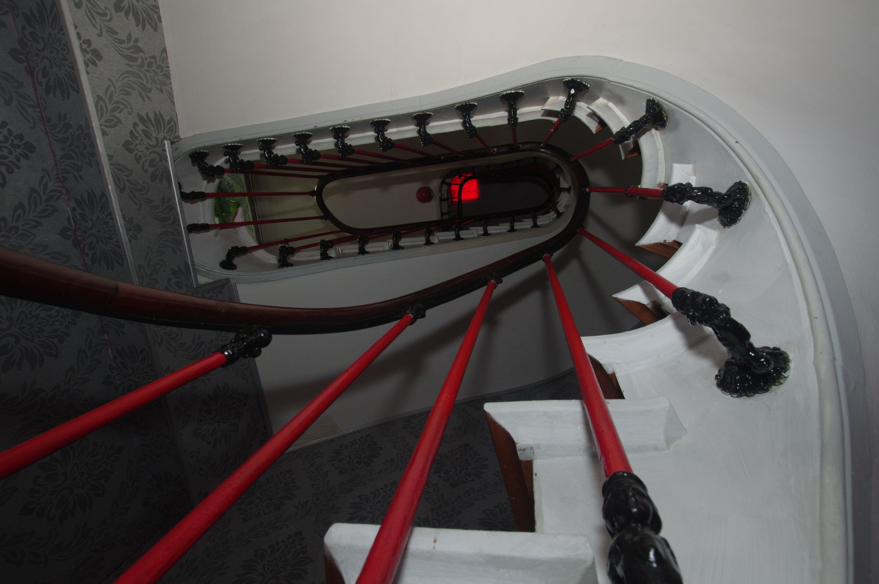 A staircase with red handrails and black balusters.