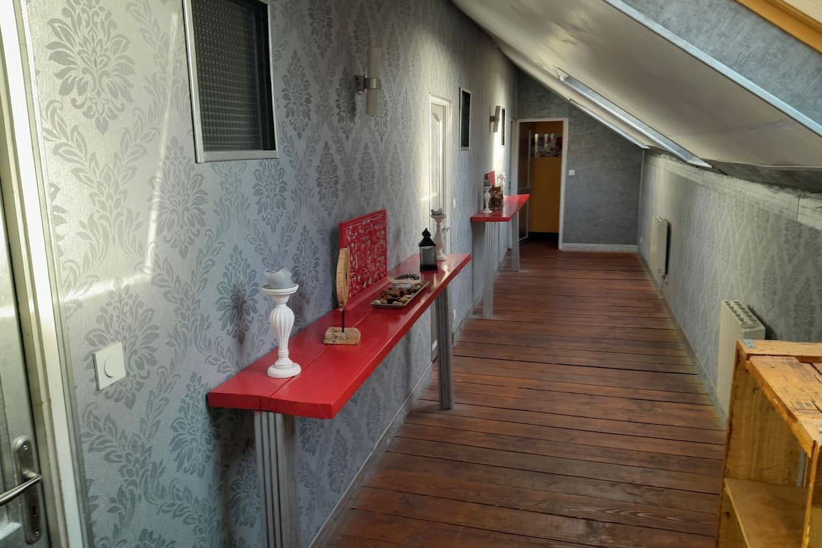 Un couloir étroit avec un papier peint à motifs, un plancher en bois et des bancs rouges.