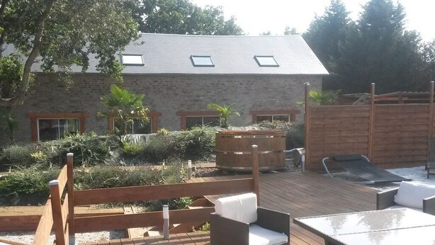 A wooden deck with outdoor seating, a swimming pool, and a stone building with windows. - Le Domaine de la Belle Normandie (Condé-en-Normandie)