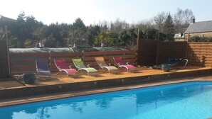 A swimming pool with wooden deck and colorful lounge chairs. - Le Domaine de la Belle Normandie (Condé-en-Normandie)