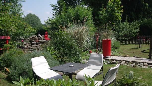A garden with a seating area, a red mailbox, and a stone wall.