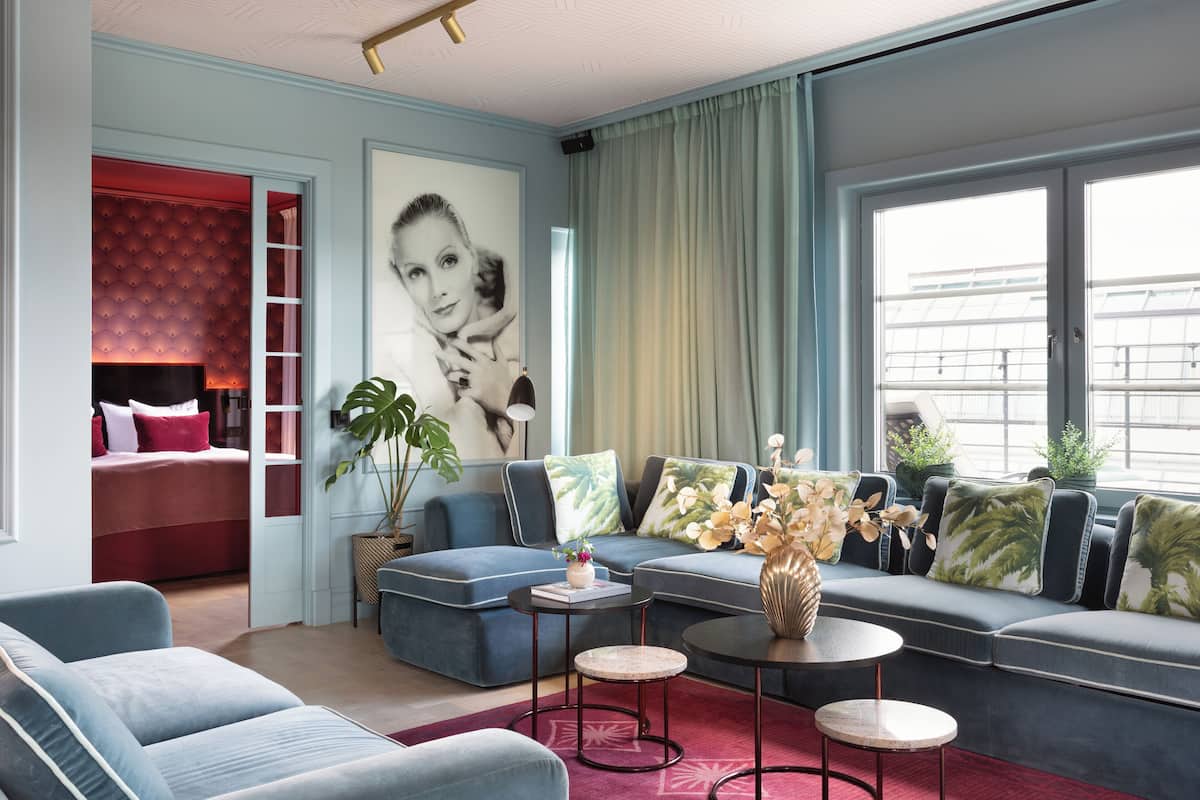 Un salon moderne avec un canapé d’angle, une petite table basse et un mur d’accent rouge.