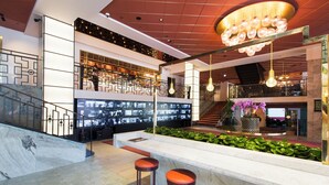 Un vestíbulo moderno con un mostrador de recepción de mármol, dos taburetes de bar, una escalera y una lámpara decorativa en el techo.