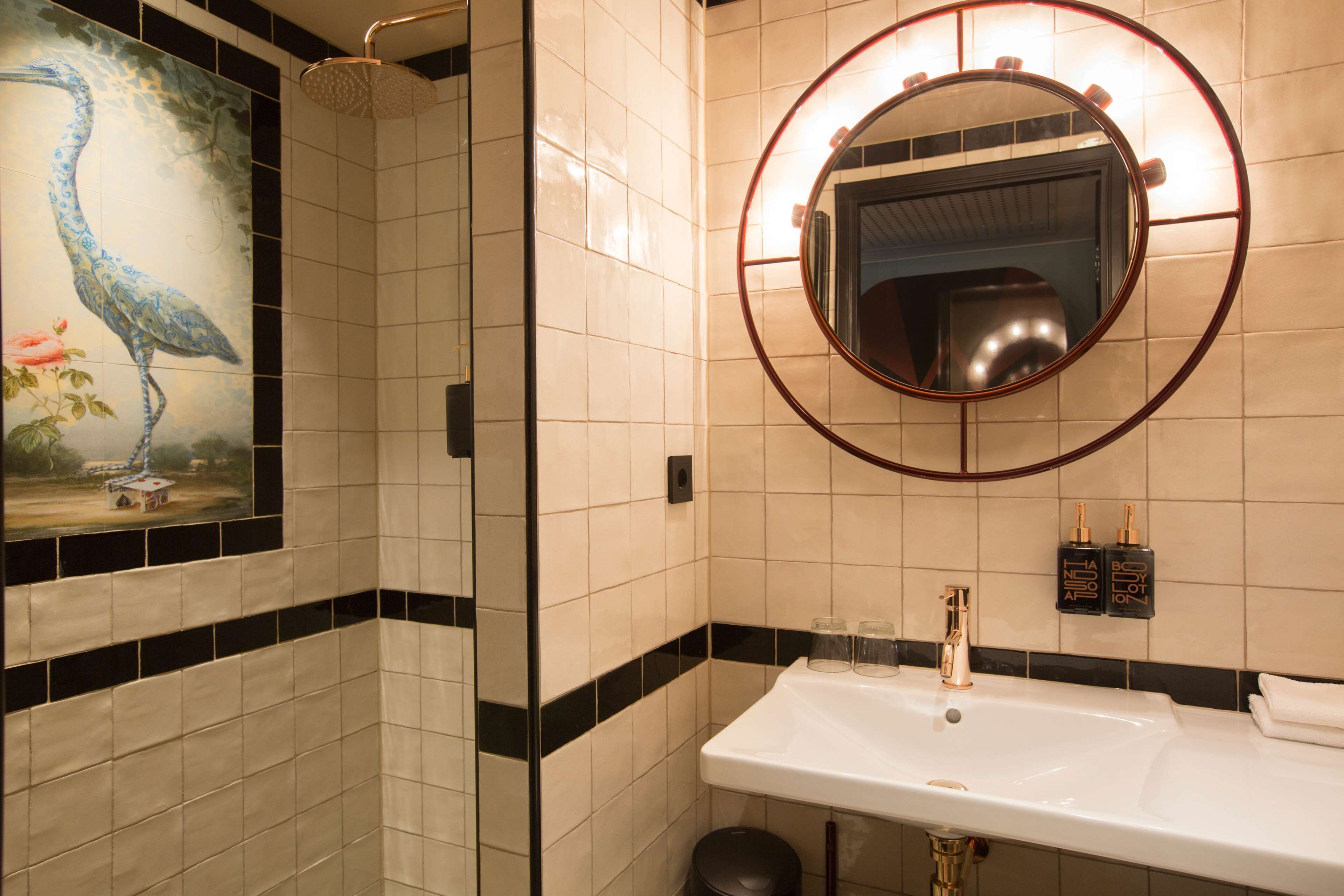 A bathroom with a white sink, a mirror with a circular frame, and a shower.