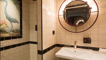 A bathroom with a white sink, a mirror with a circular frame, and a shower.