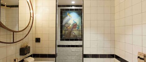 A bathroom with a white sink, a round mirror, and a decorative tile mural featuring birds.