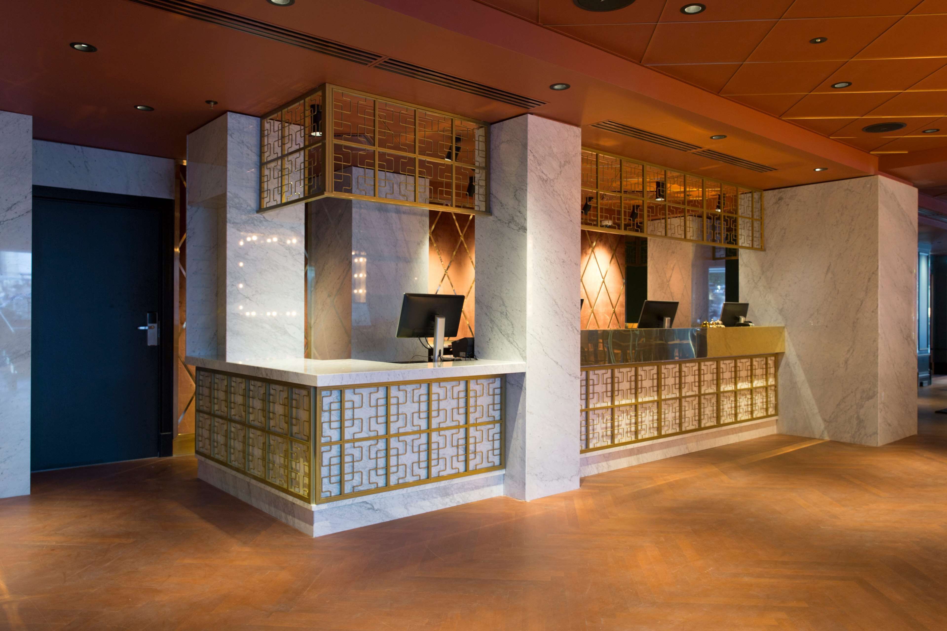 A reception area with marble walls, a reception desk, and a patterned glass partition.