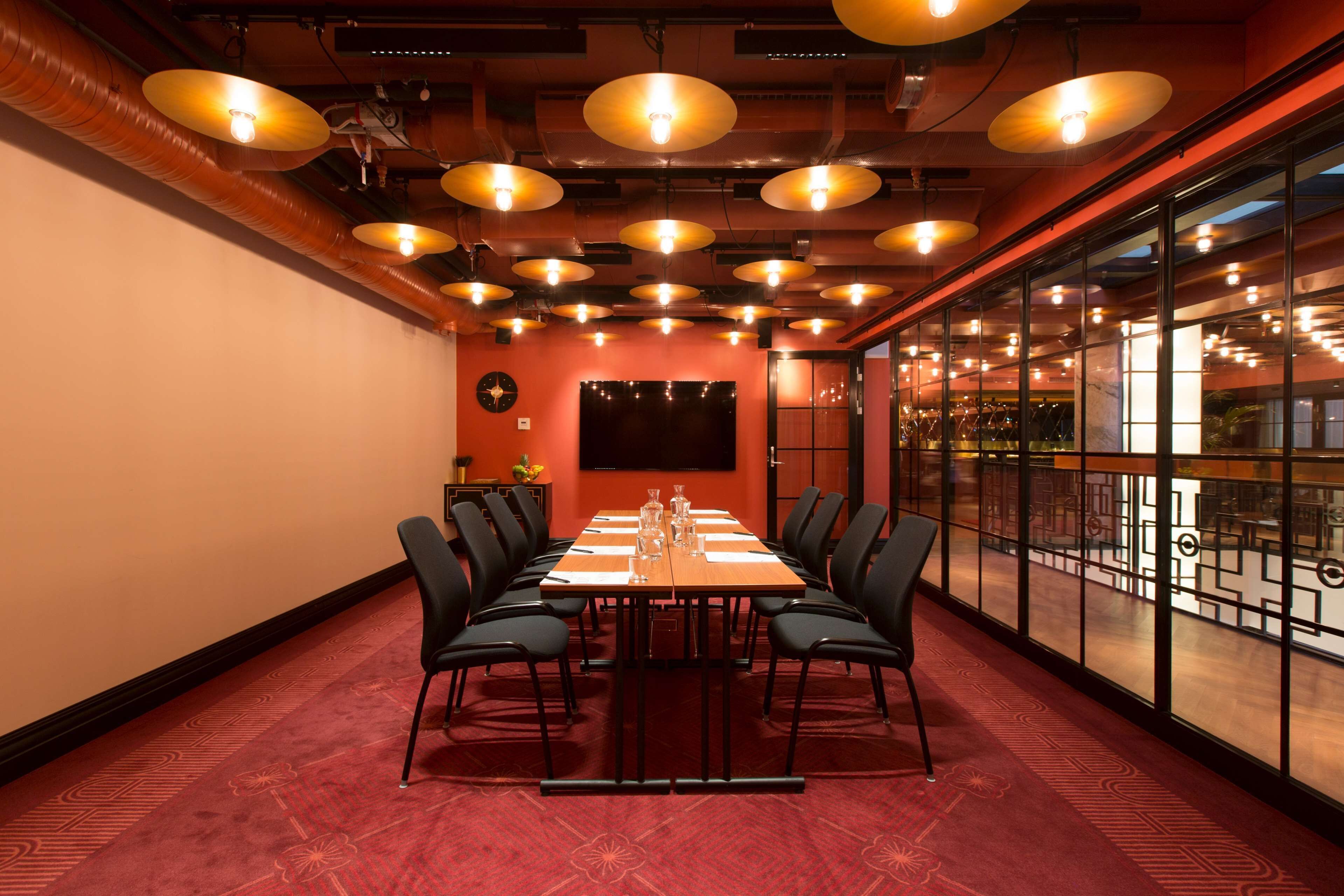 A conference room with a long table, black chairs, and a red carpet.