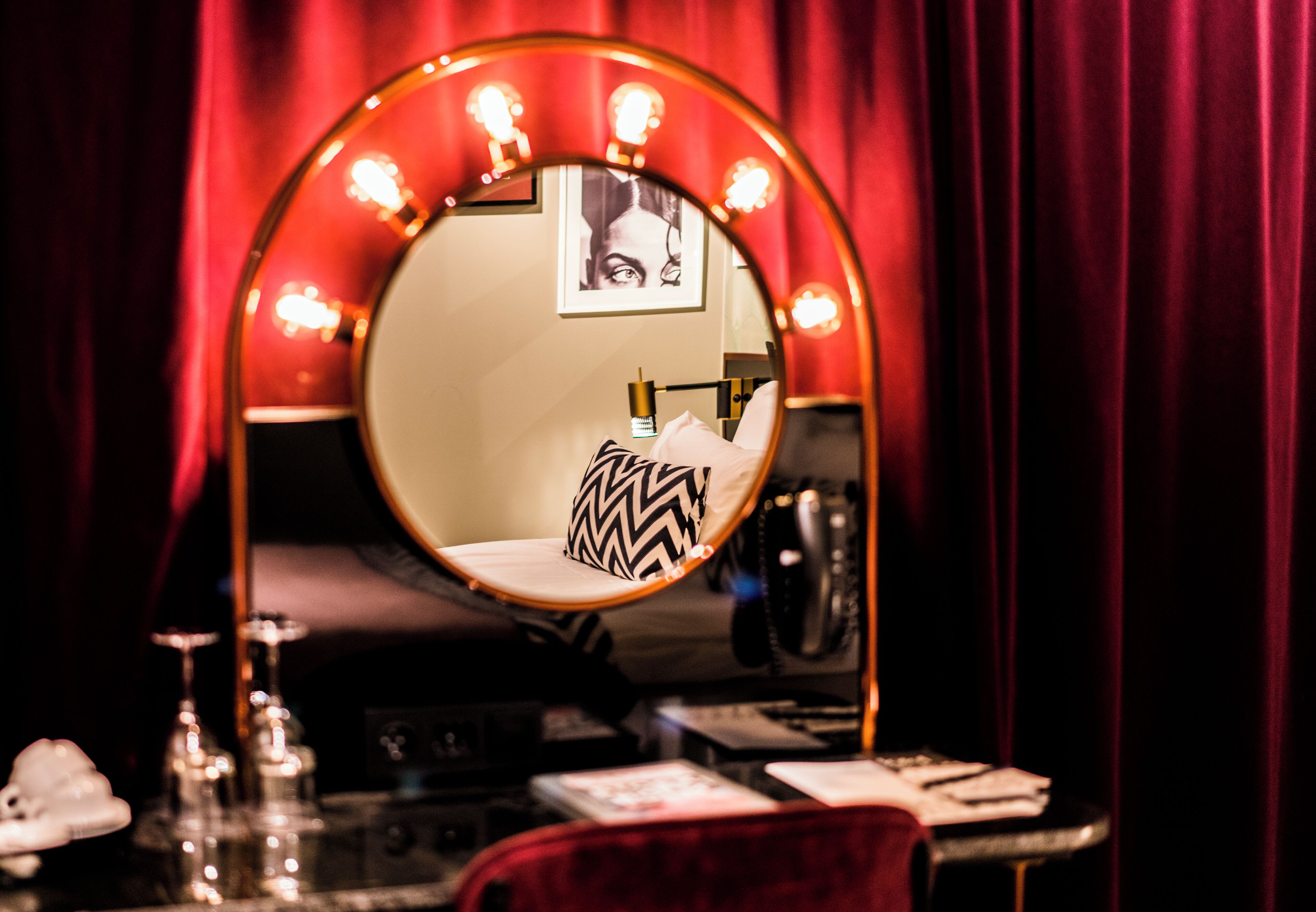 A vanity with a mirror, red curtains, and a black telephone.
