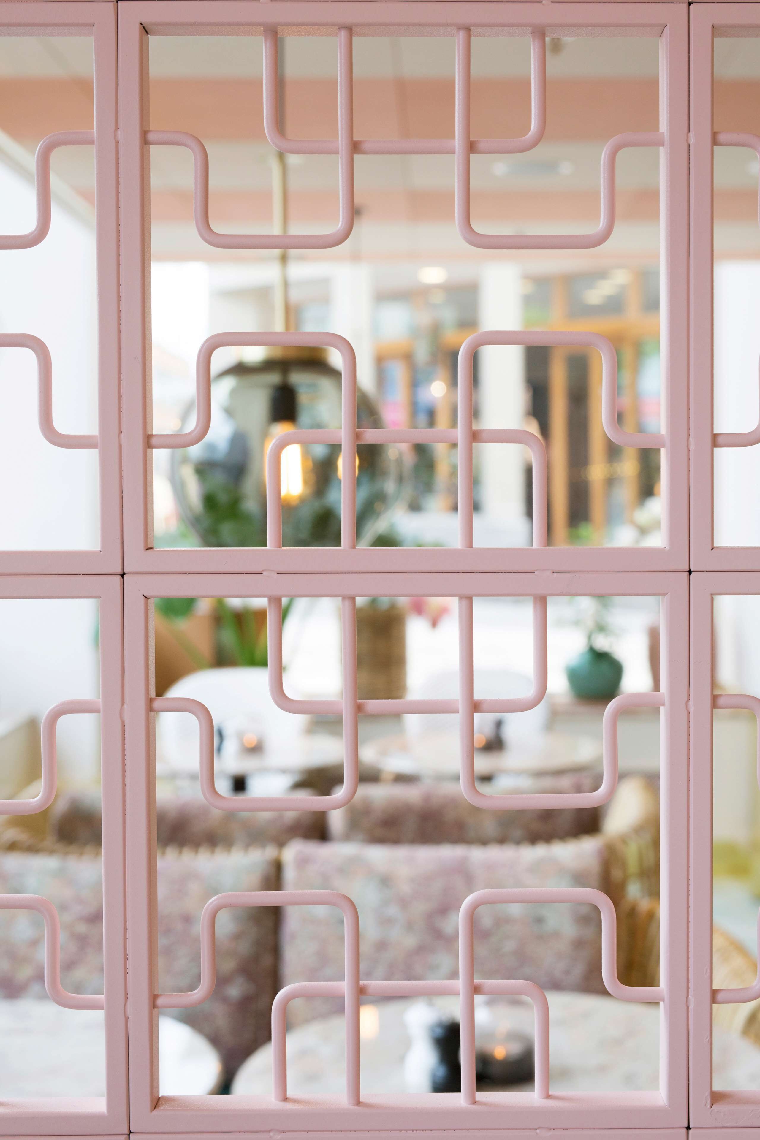A room with a pink geometric partition, a sofa, and a table with a candle.
