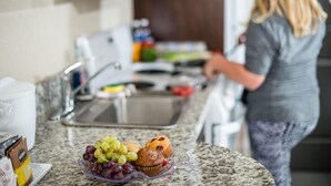 Una encimera de cocina con un plato de uvas y muffins, un fregadero y una persona al fondo.