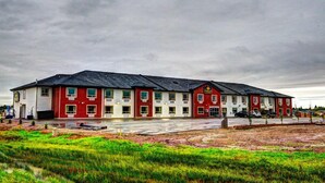 Un edificio grande de varios pisos con fachada roja y blanca, que cuenta con múltiples ventanas y una entrada central.