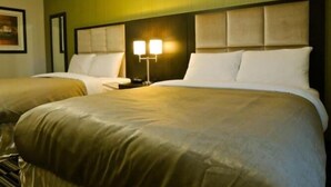 A hotel room with two beds, a headboard with a light fixture, and a green wall. - Carlyle Western Star Inn & Suites (Carlyle)