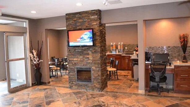A modern lobby with a stone fireplace, a TV mounted on the wall, and a reception desk. - Carlyle Western Star Inn & Suites (Carlyle)