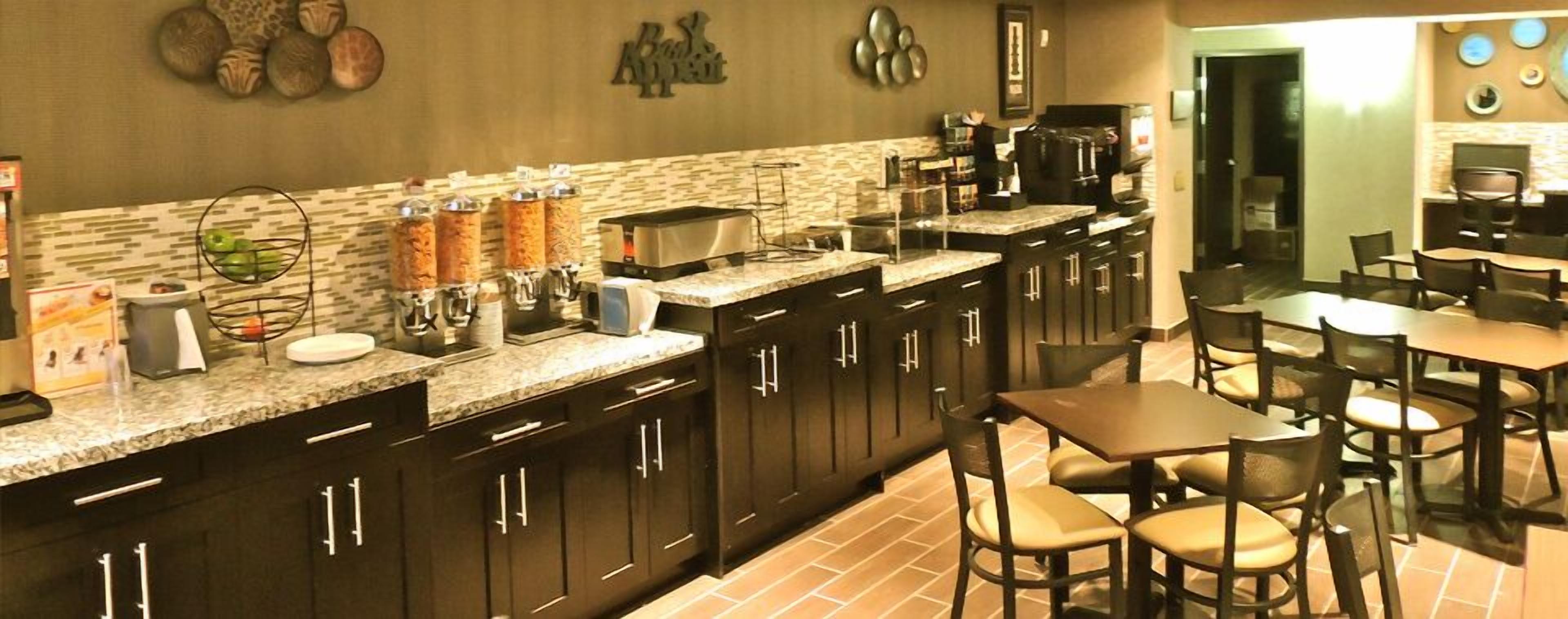 A kitchen with dark wooden cabinets, a granite countertop, and a coffee station.