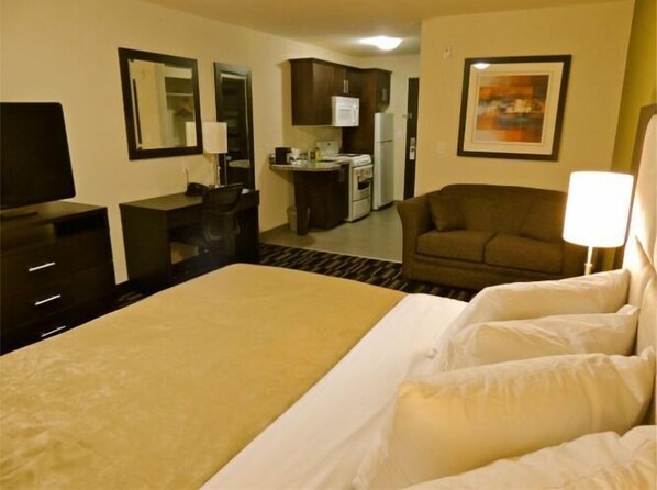 A hotel room with a bed, a desk, a chair, a kitchenette, and a TV. - Stoughton Western Star Inn & Suites (Stoughton)