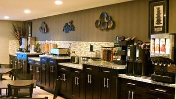 A modern kitchen with dark cabinetry, a marble countertop, and a coffee machine.