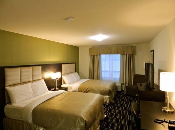 A hotel room with two beds, a desk, a chair, a TV, and a window with curtains. - Stoughton Western Star Inn & Suites (Stoughton)