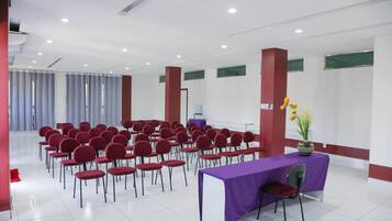 A conference room with rows of red chairs, a purple table, and a whiteboard.