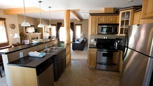 A modern kitchen with stainless steel appliances, wooden cabinets, and pendant lighting. - Red Mountain Village Condos (Rossland)