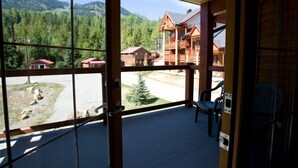 A balcony with a view of a mountainous area and a wooden building. - Red Mountain Village Condos (Rossland)