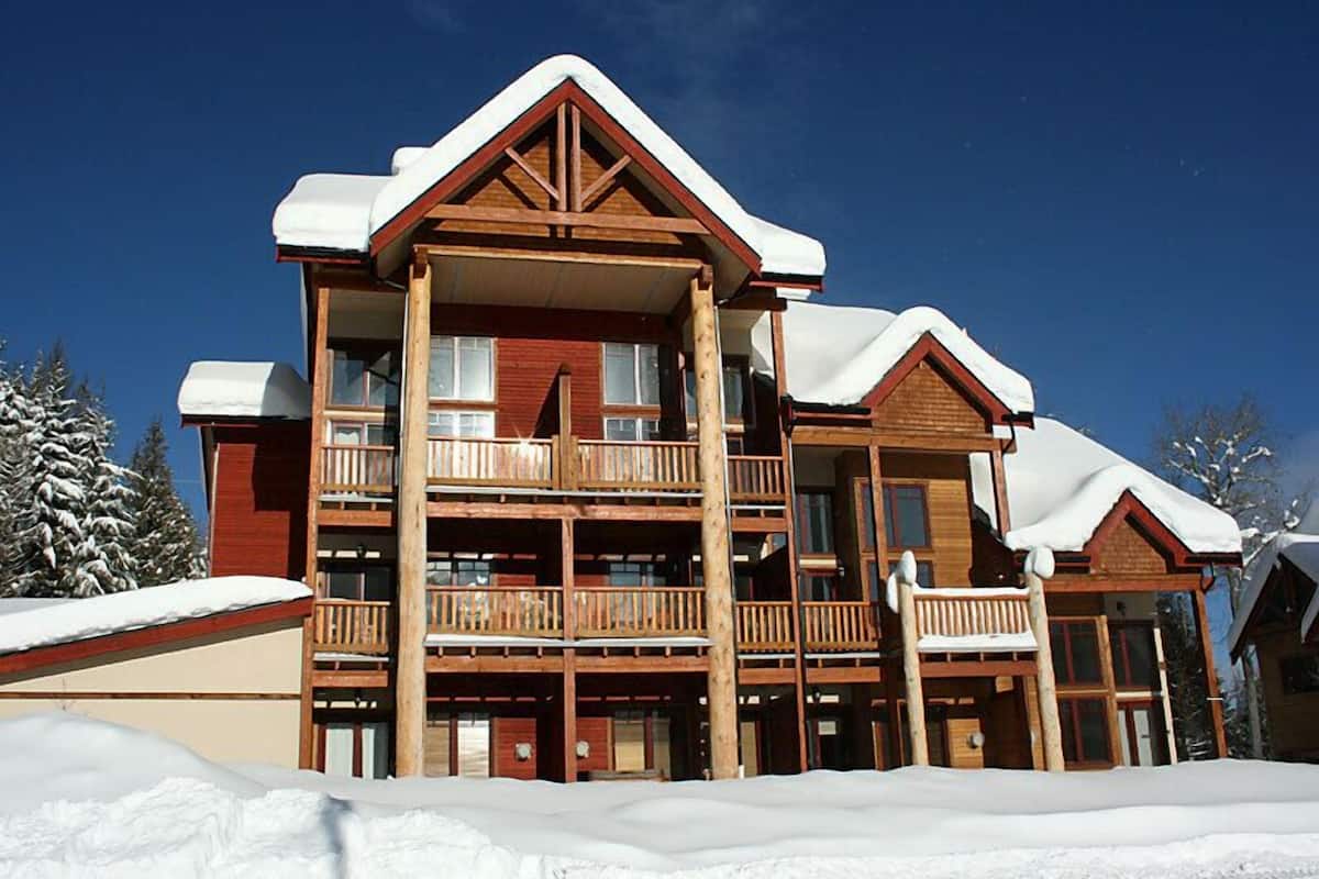 A multi-story wooden lodge with balconies and a snow-covered roof.
