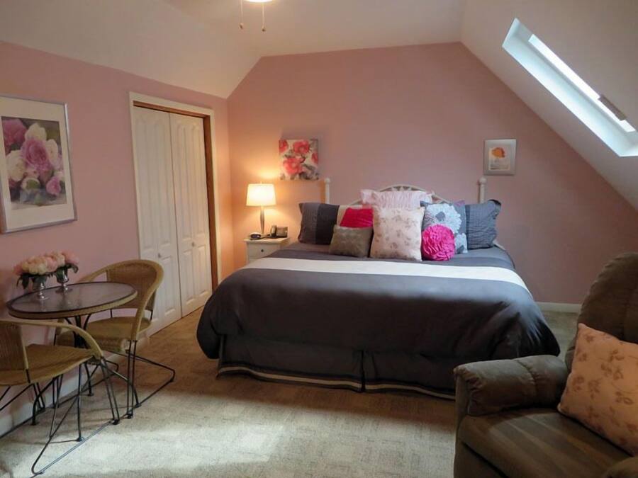 A bedroom with a bed, a nightstand, a lamp, a chair, and a couch.