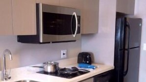 A compact kitchen with a microwave, toaster, sink, and black refrigerator. - Western Star All Suites Melita (Melita)