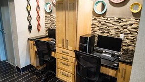 Un espacio de oficina moderno con dos escritorios, dos sillas, un armario de madera y espejos decorativos en la pared.