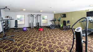 Gimnasio de hotel con máquinas de cardio, equipo de pesas y pelotas de ejercicio.