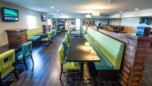 Un restaurante con cabinas y mesas, suelo de madera y un televisor en la pared.