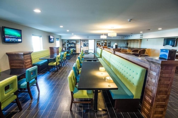 A restaurant with booths and tables, wooden flooring, and a TV on the wall.