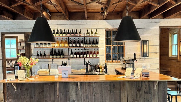 A rustic bar area with wooden beams, a wooden counter, and a wine rack.