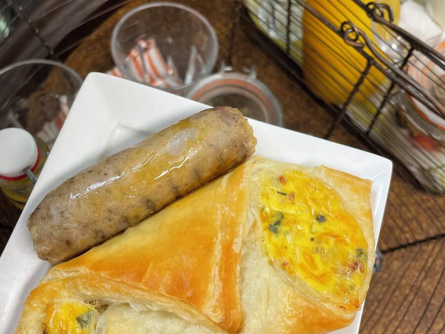 A plate with two sausages and a pastry.