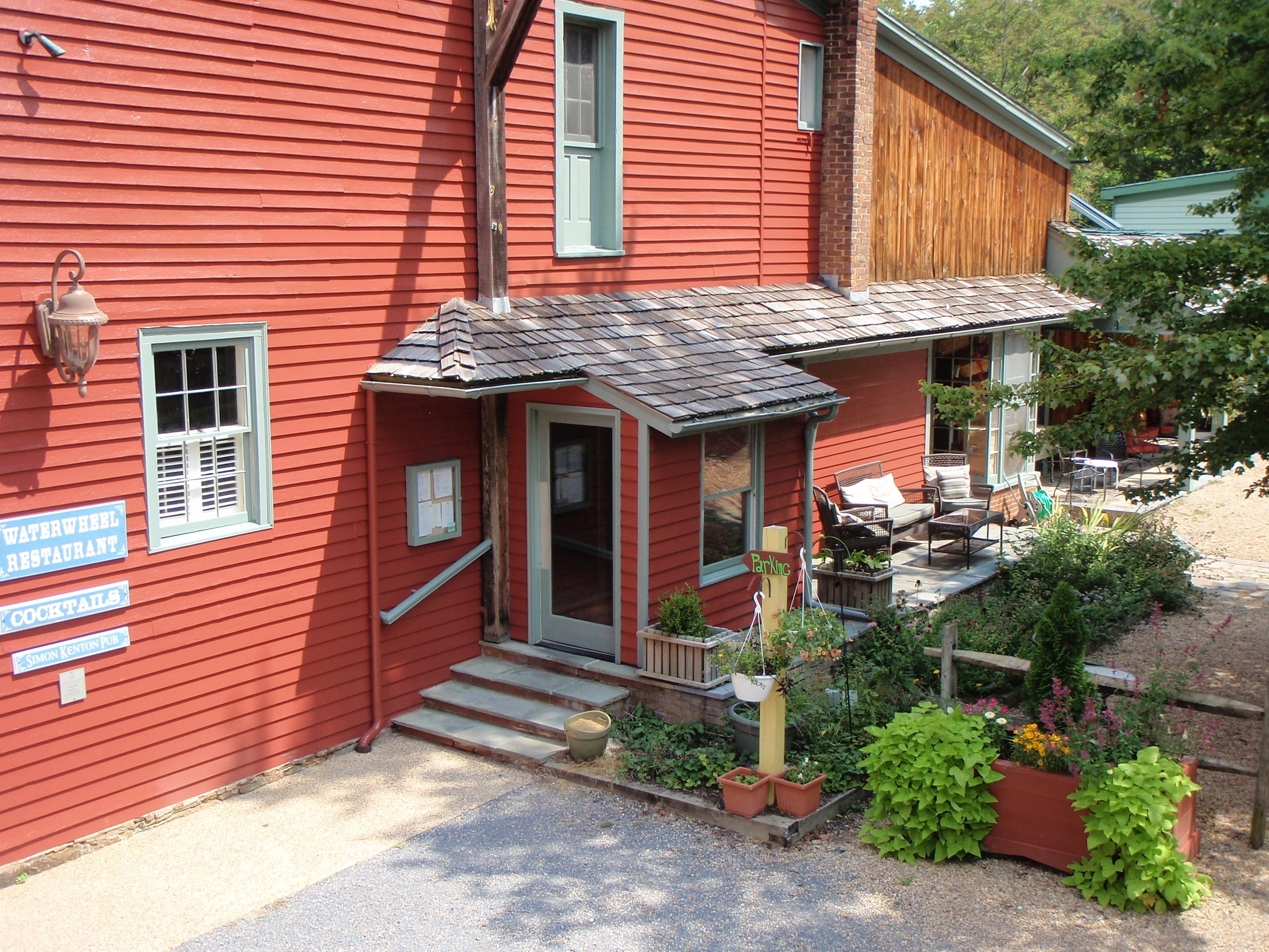 Un bâtiment rouge avec un porche, une enseigne indiquant un restaurant et des tables à l’extérieur.