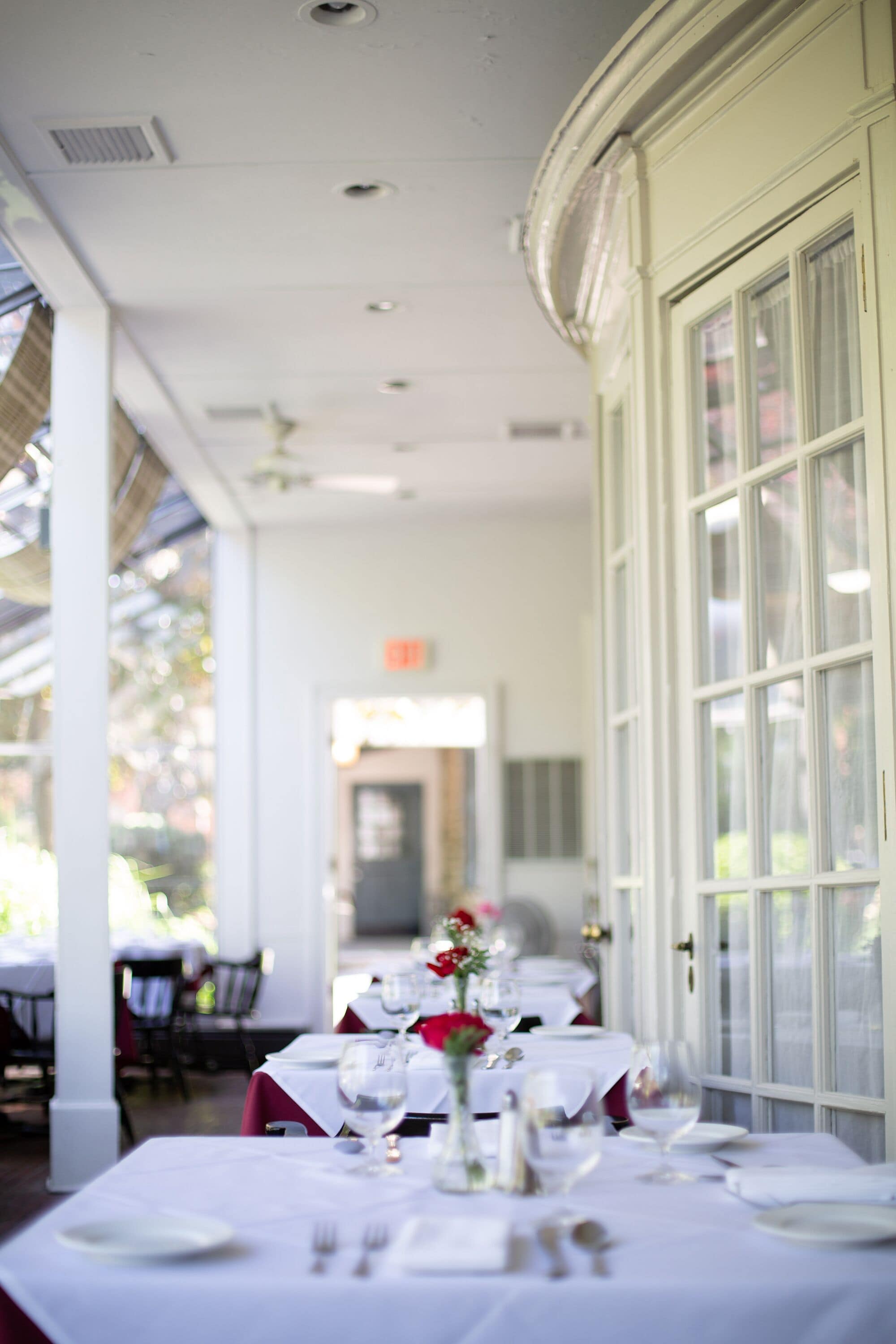 A dining area with tables set for a meal, featuring white tablecloths and red napkins.